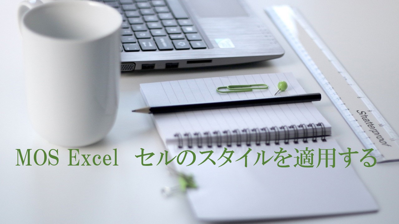 パソコン・マグカップ・ノートなどがデスクにおいてある。MOS Excel　セルのスタイルを適用すると書いてある