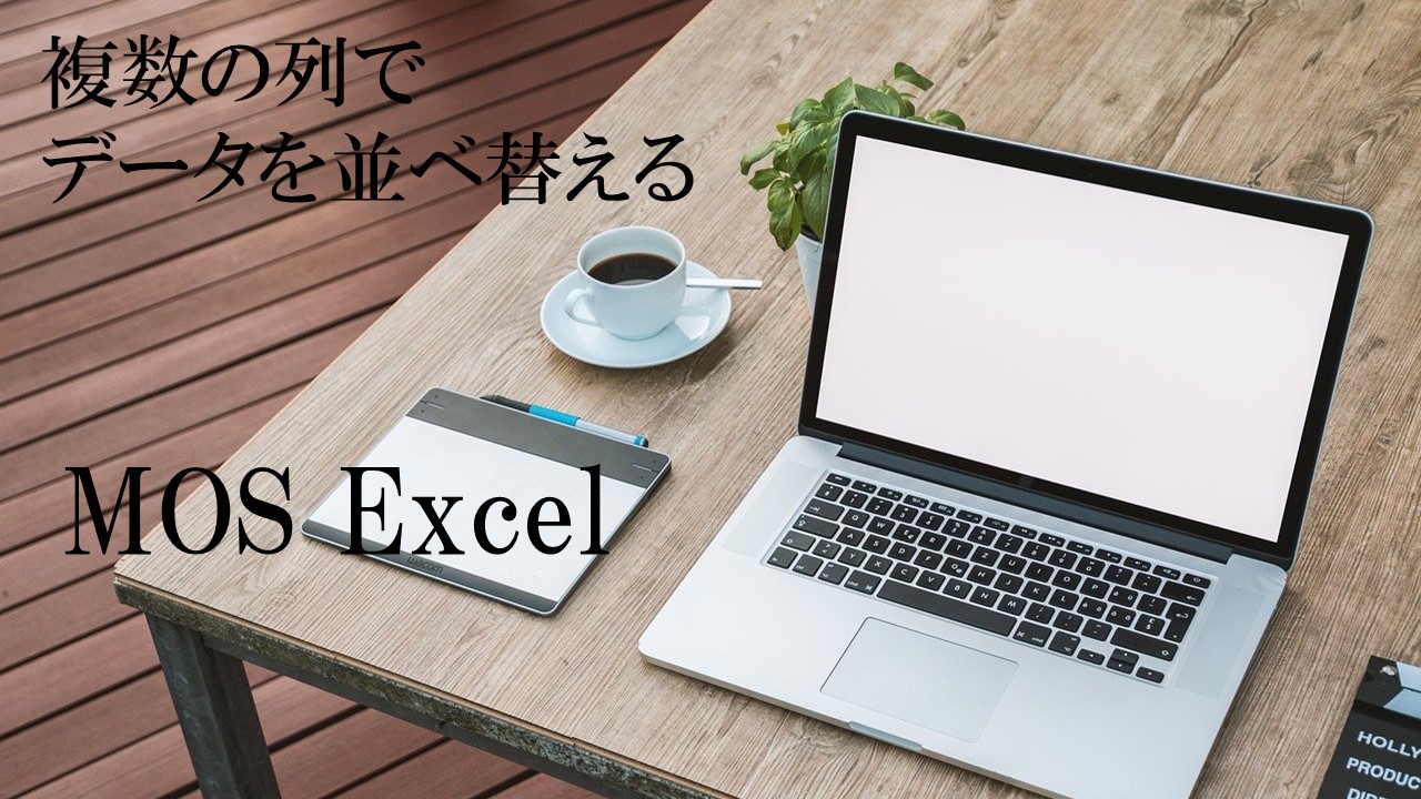 テーブルの上にパソコンとコーヒーなどが置いてある。MOS Excel　複数の列でデータを並べ替えると書いてある